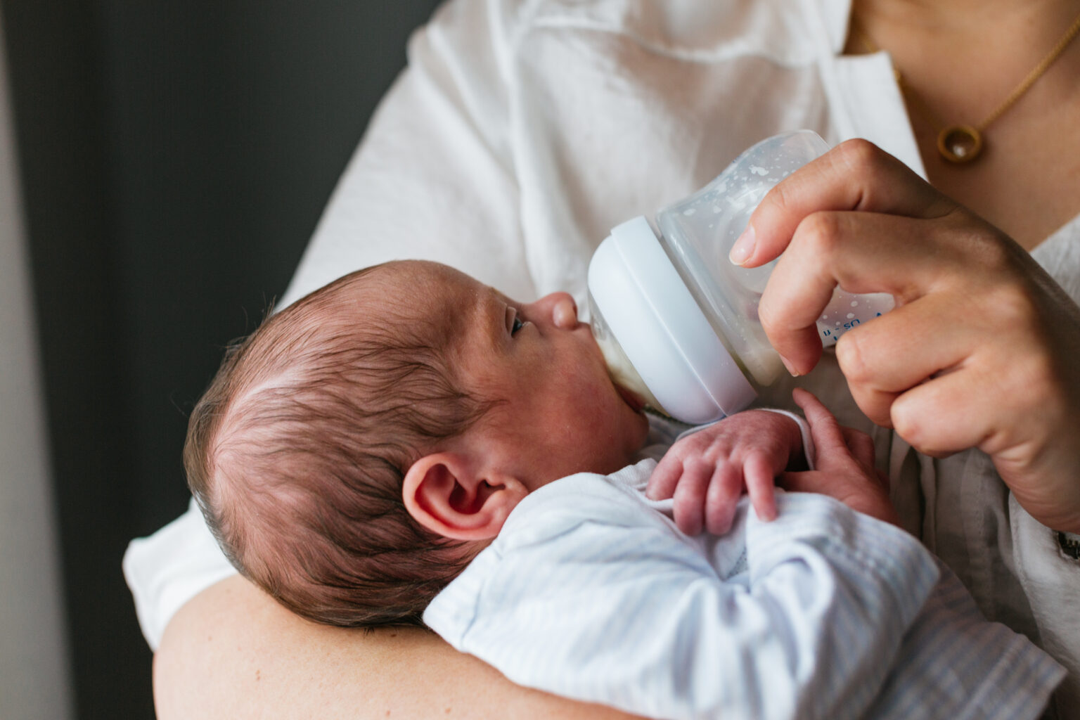 A parent feeding an infant with a bottle